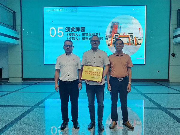闽发铝业生产中心副总经理王育生先生（右）向蓝狮注册咨询集团颁发牌匾